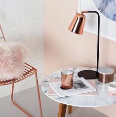 a marble table topped with a pink chair next to a lamp