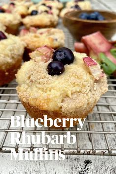 Blueberry topped muffin on a cooling rack with rhubarb and a bowl of blueberries in the background. Blueberry Rhubarb Muffins, Unusual Muffin Recipes, Rhubarb Blueberry Recipes, Baked Rhubarb, Mulberry Muffins, Baking Deserts, Blueberry Crumble Muffins, Comforting Recipes, Recipes Muffins