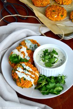 some food is sitting on a white plate and next to a bowl of ranch dressing