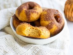 a white bowl filled with donuts on top of a table next to an orange pumpkin