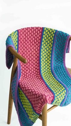 a multicolored knitted blanket sitting on top of a wooden chair