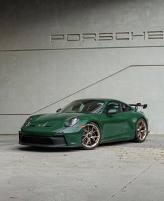 a green sports car parked in front of a porsche logo