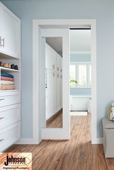 an open door leading to a bathroom with white cabinets and drawers on either side of the room