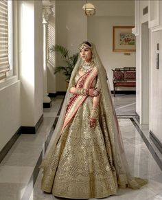 a woman in a gold and red bridal gown posing for the camera with her hands on her hips