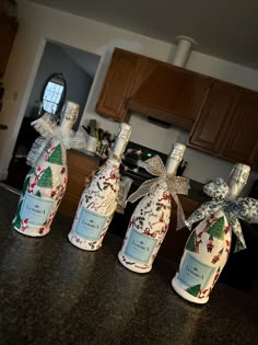 three wine bottles wrapped in paper and tied with bows sitting on a kitchen counter top