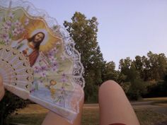 a person holding an umbrella with the image of jesus on it in front of trees