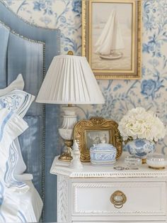 a bedroom with blue and white wallpaper, gold trimmings and a lamp