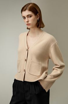 Made of 70% wool and 30% cashmere, this drop-shoulder V-neck cardigan with classic horn buttons is an essential for the autumn wardrobe. Pair it with dresses, skirts, or pants, and looks particularly elegant when paired with tall boots. 70% Wool+30% Cashmere Dropped Shoulder Sleeves Front Pockets Loose Fit Ribbed Hems