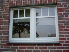 a brick building with a white window and tree reflection in the window pane on it