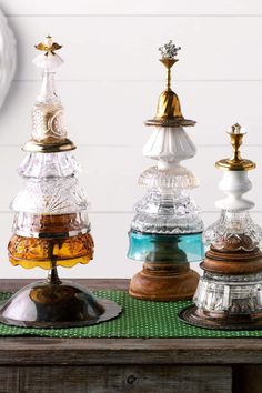 three different colored glass jars sitting on top of a green tablecloth next to a clock