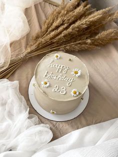 a birthday cake sitting on top of a table next to some dry grass and flowers