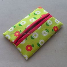 a small green flowered wallet with red and white flowers on the front, sitting on a gray surface