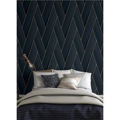 a bed with pillows and blankets in front of a dark blue wallpapered bedroom