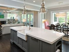 a large kitchen with an island in the middle and two pendant lights hanging from the ceiling