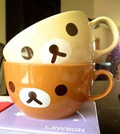 two cups with faces painted on them sitting on top of a table next to each other