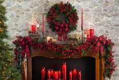 a mantel decorated with red candles and wreaths