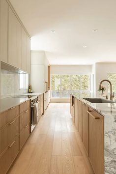 a large kitchen with wooden cabinets and marble counter tops, along with hardwood flooring