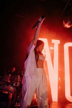 a woman standing on top of a stage with her arms in the air while holding a microphone