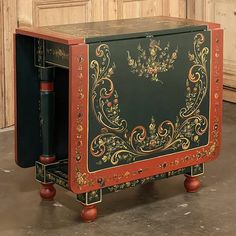 an ornately painted wooden box on wheels sits in the middle of a room with wood paneling