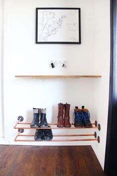 shoes are lined up on a shelf in front of a door with a framed picture above it