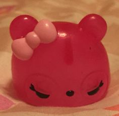 a pink bear toy with big ears on it's head sitting on a bed