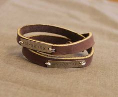 two leather bracelets sitting on top of a bed