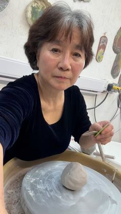 an older woman is making something out of clay