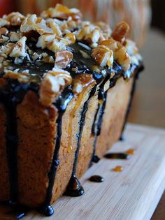 a cake with nuts and chocolate drizzled on it's top sitting on a plate