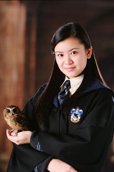 a young woman holding an owl in her hand while wearing a school uniform and smiling at the camera