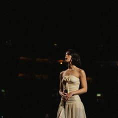 a woman standing in the dark wearing a dress