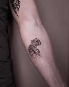 a woman's arm with a cheetah tattoo on the left side of her arm