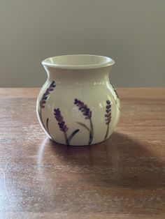 a white vase sitting on top of a wooden table