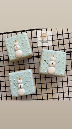 three decorated cookies sitting on top of a cooling rack