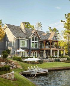 a large house sitting on top of a lush green field next to a lake with lots of trees