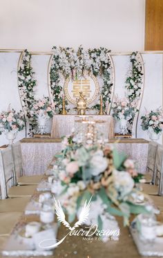 the table is set up for a wedding reception with flowers and greenery on it