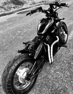 a black and white photo of a motorcycle parked on the side of the road with no one around it