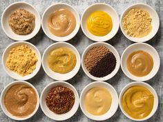 nine bowls filled with different types of peanut butter and other foodstuffs on a table