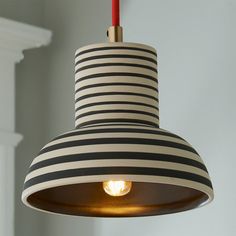 a black and white striped light hanging from a ceiling fixture with a red cord attached to it