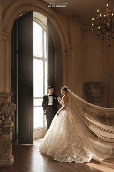 a bride and groom standing in front of a large window