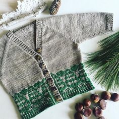 a knitted sweater next to some nuts and pine cones on a white table top