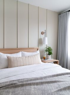 a bed with white sheets and pillows next to a window