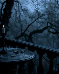 a candle that is sitting on top of a table in the dark night with trees behind it