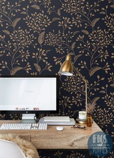 a desktop computer sitting on top of a wooden desk next to a wallpapered wall