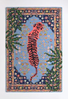 a blue rug with a tiger on it's back and flowers in the background