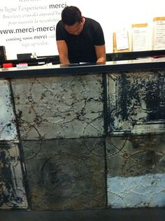 a man sitting at a counter in front of a wall with writing on the walls