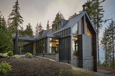 a modern house in the woods with lots of windows on it's roof and side walls