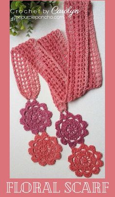 the crochet scarf is made with pink yarn and has three flowers on it