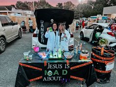 two women standing in front of a table with food and drinks on it that says jesus is mad about