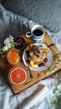 the breakfast is ready to be eaten on the bed with fruit and juice in bowls