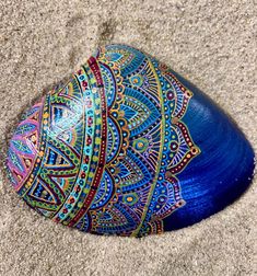 a painted rock sitting on top of a sandy beach